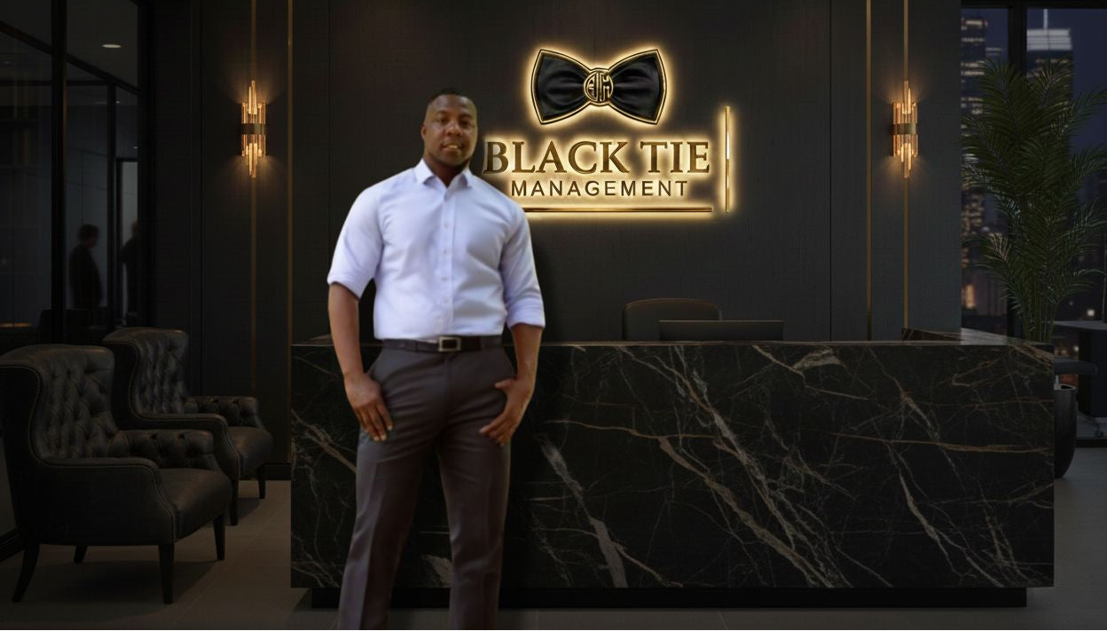 Man standing in front of a reception desk with 'Black Tie Management' logo